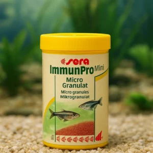 Akvaryum önünde duran Sera ImmunPro Mini Nature 100ml yem kutusu